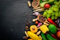 A large selection of raw vegetables, fruits and spices on a black wooden surface. Free space for your text. Royalty Free Stock Photo