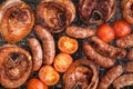 large shank steaks with pork sausages and tomato halves are grilled on a charcoal grill. advertisement of a summer street cafe.