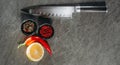 A large sharp kitchen knife with a black handle, next to two black cups with red pepper and mix, hot red pepper and a cut piece of Royalty Free Stock Photo