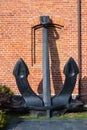 Large ship anchor against a red brick wall on a sunny day Royalty Free Stock Photo