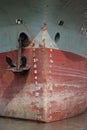 Large ship front close up shot on a riverbank. Rusty anchor hanging on the ship. Old ship front with scratches and water meter.