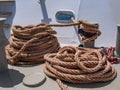 Large ship ropes folded to dry on the deck of a ship on a sunny day.