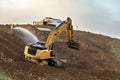 Large shovel excavator on the side of a hill with a man spraying water Royalty Free Stock Photo