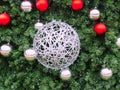 A large silver wicker ball entwined with a garland hangs in the center in the fir branches with small red and silver Royalty Free Stock Photo