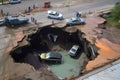 large sinkhole with cars and trucks falling into the depths