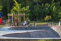 Large skate pool, teenager rides scooter on steep slopes