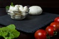 Large and small balls of mozzarella cheese on a stone plate with basil leaves, lettuce, tomatoes and hot pepper Royalty Free Stock Photo