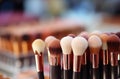 Large and small makeup brushes of various colors assembled in a bundle on the desktop. The concept of cosmetologist\'s tools.