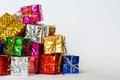 Large and small multicolored shiny boxes with gifts lie on a white background. Festive foil packaging