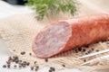 Large smoked salami sausage cut in half on rustic background