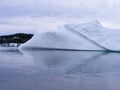 Large smooth iceberg in Twillingate Harbour with homes on the horizon Royalty Free Stock Photo