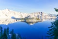 Large snow cliff and pine trees lush in Crater Lake with snowcap mountain and Wizard island reflection Royalty Free Stock Photo