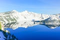 Large snow cliff and pine trees lush in Crater Lake with snowcap mountain and Wizard island reflection Royalty Free Stock Photo