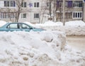 Large snowdrifts against the backdrop of a city street with a car. Royalty Free Stock Photo