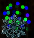 A large snowflake on a bokeh background of green blue New Year`s lights. Royalty Free Stock Photo