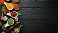 Large spice and herb collection in bowls and spoons. Indian spices. On a black wooden background.