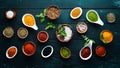 Large spice and herb collection in bowls and spoons. Indian spices. On a black wooden background.