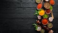 Large spice and herb collection in bowls and spoons. Indian spices. On a black wooden background.