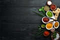 Large spice and herb collection in bowls and spoons. Indian spices. On a black wooden background.