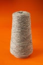 A large spool of beige harsh threads on an orange background