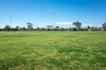A large sports ground with green grass with many suburban residential houses in the distance. Background texture of a public park Royalty Free Stock Photo