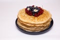 A large stack of pancakes with red sweet berries