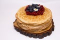 A large stack of pancakes with red sweet berries