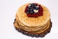 A large stack of pancakes with red sweet berries