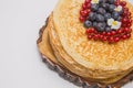 A large stack of pancakes with red sweet berries