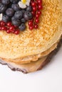 A large stack of pancakes with red sweet berries