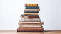 A large stack of vintage books with white, blue, green, and red covers and books is sitting on a wooden table Royalty Free Stock Photo