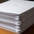 A large stack of white printer paper sits on a wooden surface Royalty Free Stock Photo