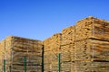 Large stacks of wooden planks at the sawmill yard on the blue sky background