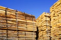 Large stacks of wooden planks at the sawmill yard on the blue sky background