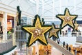 Large stars New Year Christmas decor in shopping mall interior, escalator, glass roof atrium. Pavlodar, Kazakhstan - 01.17.2023