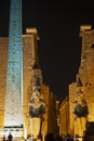 Statue and obelisk at entrance to Luxor Temple during night Royalty Free Stock Photo