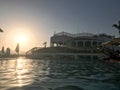 A large stone building near the water, a pool against the blue sky and a big sun, a sunset in the evening in a tropical seaside re Royalty Free Stock Photo