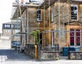 Large stone built fully scaffolded house or small business undergoing renovations
