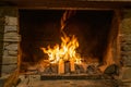 Large stone fireplace with burning fire and firewood on metal stand. Cozy warm and calm moments at cold season, heater Royalty Free Stock Photo