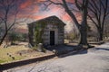 a large stone mausoleum in the graveyard with bare winter trees and lush green trees and powerful cloudsat sunset Royalty Free Stock Photo