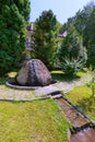 A large stone from which the fountain flows along the background of large juniper trees Royalty Free Stock Photo