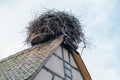 Large stork nest on the roof gable of a traditional wooden half-timbered house in the Alsace region of France