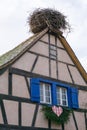 Large stork nest on the roof gable of a traditional wooden half-timbered house in the Alsace region of France