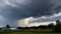 a large storm cloud looms over a farm in the distance