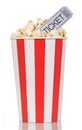 Large striped popcorn box with gray cinema ticket on white. Royalty Free Stock Photo