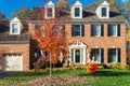 Large Suburban Brick House with Garage and Fall Holiday Decorations. Trimmed lawn and autumn leaves on green grass