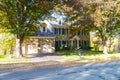 Large Suburban Brick House with Garage and Fall Holiday Decorations. Trimmed lawn and autumn leaves on green grass