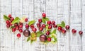 Large sweet juicy cherries, plums and grapes, foliage and flowers on a wooden background