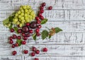 Large sweet juicy cherries, plums and grapes, foliage and flowers on a wooden background