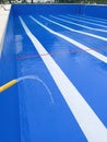 A large swimming pool with a blue background and white lines is filled with a stream of water from a yellow hose Royalty Free Stock Photo